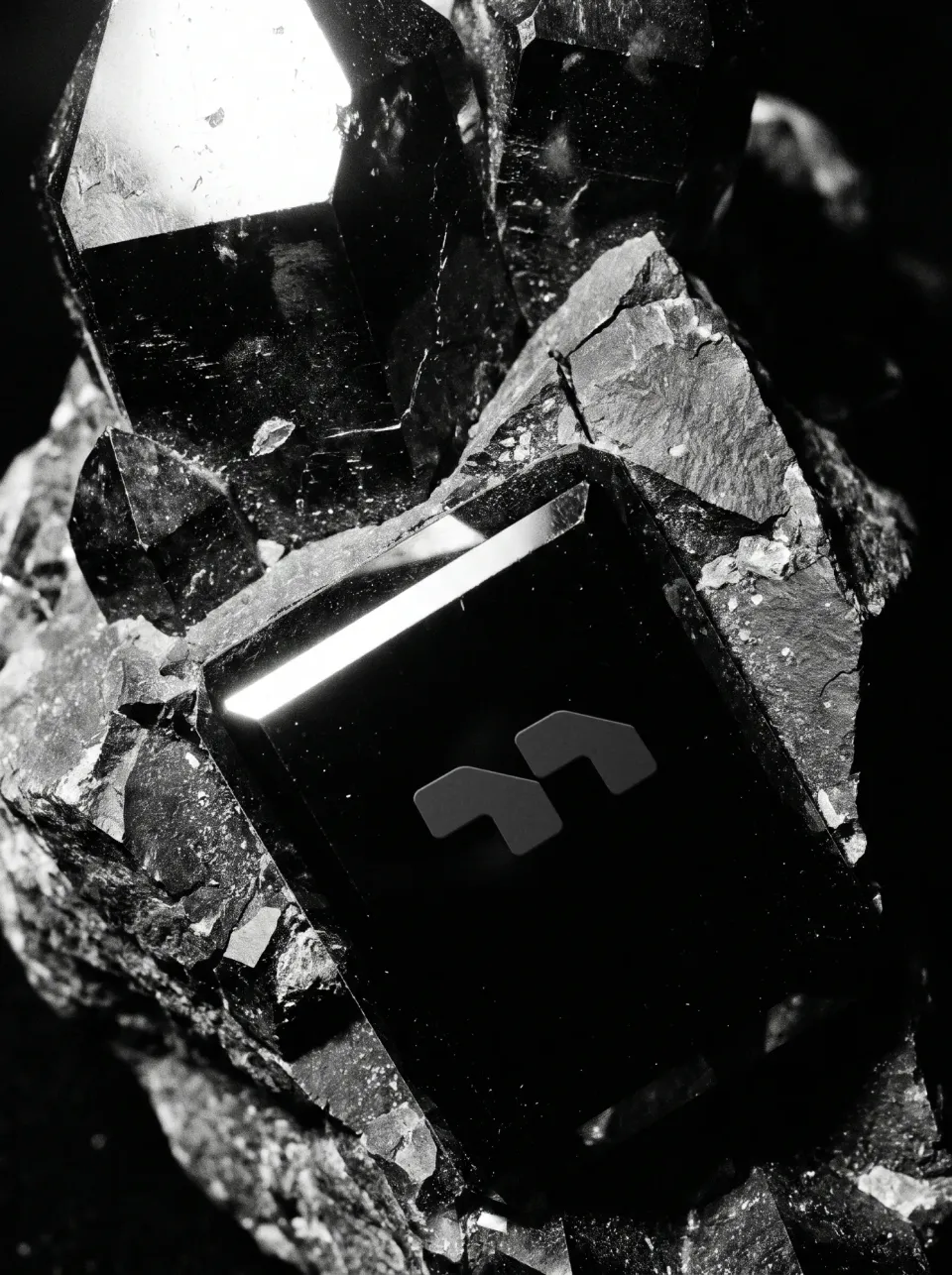 Murugathas: the mark as a matt relief on a polished black stone slab, set among dark crystals with a bright edge of light, black and white