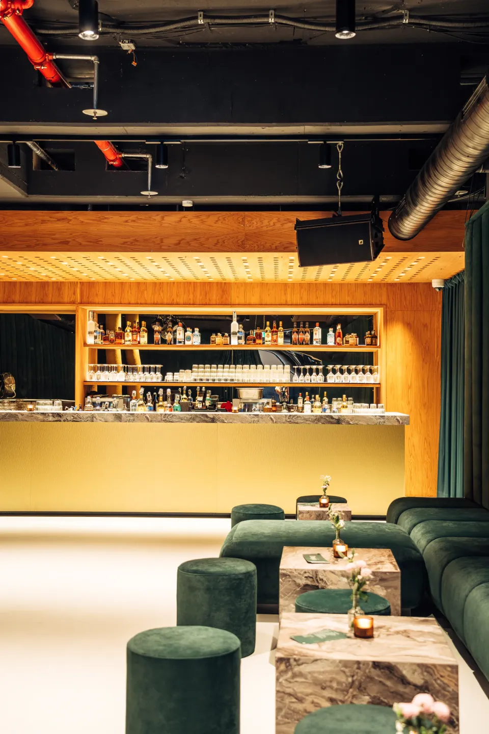OSCHO: bar with lit back bar, green velvet seating and marble tables in front